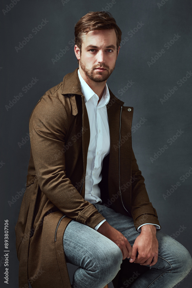 Style, portrait and man on chair in studio for confidence, trendy fashion or classy clothing on dark background. Smile, jeans and model on stool for elegant outfit, designer coat or semi formal Style, portrait and man on chair in studio for confidence, trendy fashion or classy clothing on dark background. Smile, jeans and model on stool for elegant outfit, designer coat or semi formal