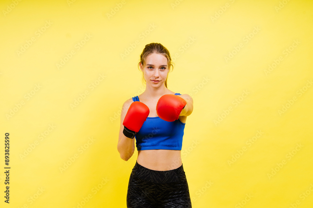 Young tired woman in sportswear and boxing gloves standing isolated on white yellow background. Young tired woman in sportswear and boxing gloves standing isolated on white yellow background.