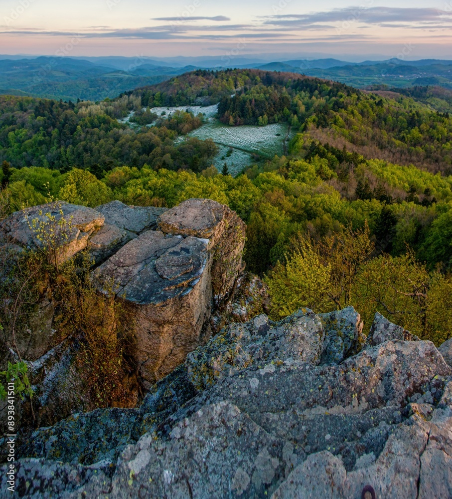View from the rocks of a beautiful mountain landscape with hills, forests and a frozen meadow during sunrise.