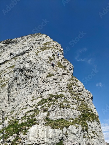 Via ferrata from Braunwald Glarus. Young men and women climbing the rock
climbs the rock up to the Eggstock mountain. Climbing in the Swiss mountains. High quality photo. photo