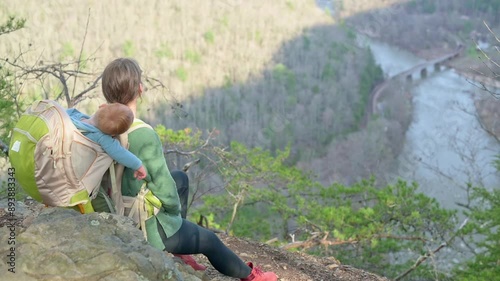 Mother sits on a cliff with her baby in a backpack carrier, overlooking the Nolichucky River along the Appalachian Trail video captures the serene and adventurous spirit of hiking and enjoying nature photo