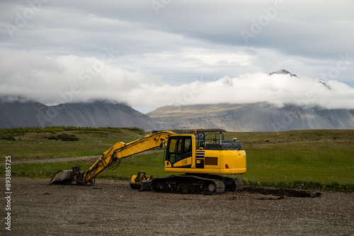 Yellow excavator on a road with mountains in the background in Iceland
