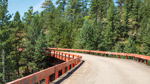 Curve in historic Adelaide bridge with red rails on Phantom Canyon Road in the Rocky Mountain in Colorado; scenic gold belt byway; concepts of adventure, scenic byway and road less traveled
