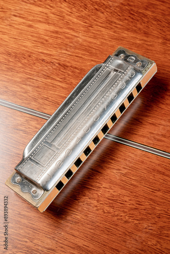 
Vintage 10-hole diatonic harmonica rest on the back of an upturned acoustic guitar

