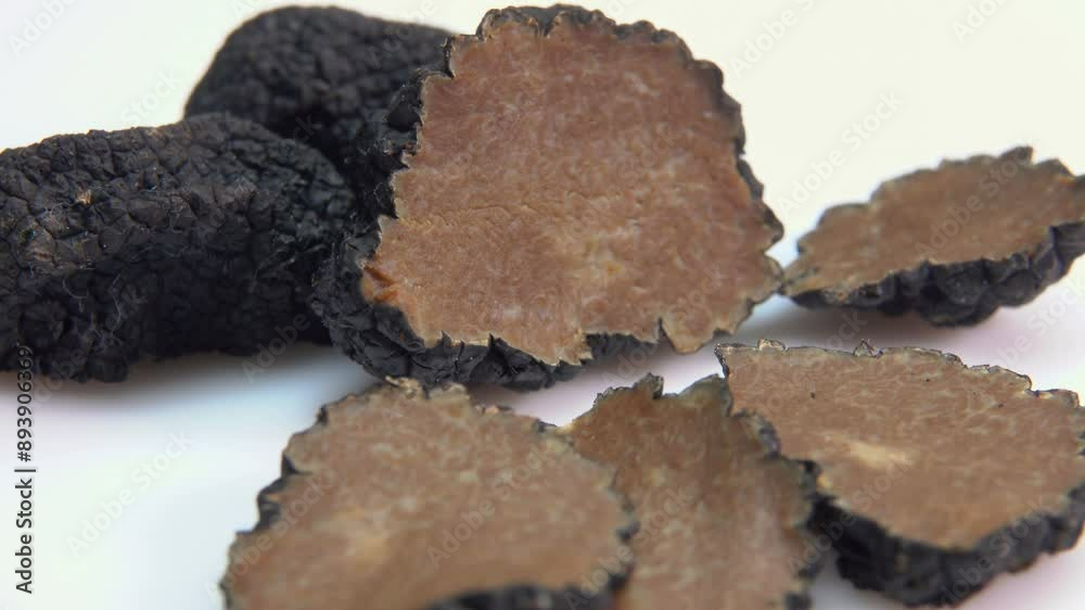 Close up of a rare black truffle fungus cutted into pieces on a white surface. Panoramic view of a texture of a black truffle Close up of a rare black truffle fungus cutted into pieces on a white surface. Panoramic view of a texture of a black truffle