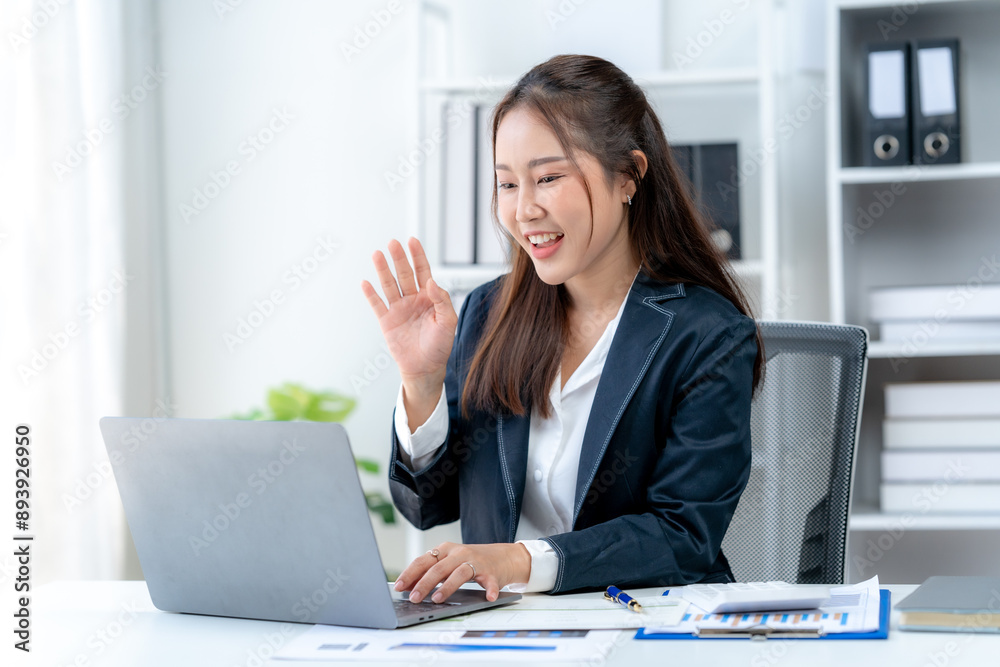 Asian business woman using computer looking at laptop and talking on video conference Asian business woman using computer looking at laptop and talking on video conference