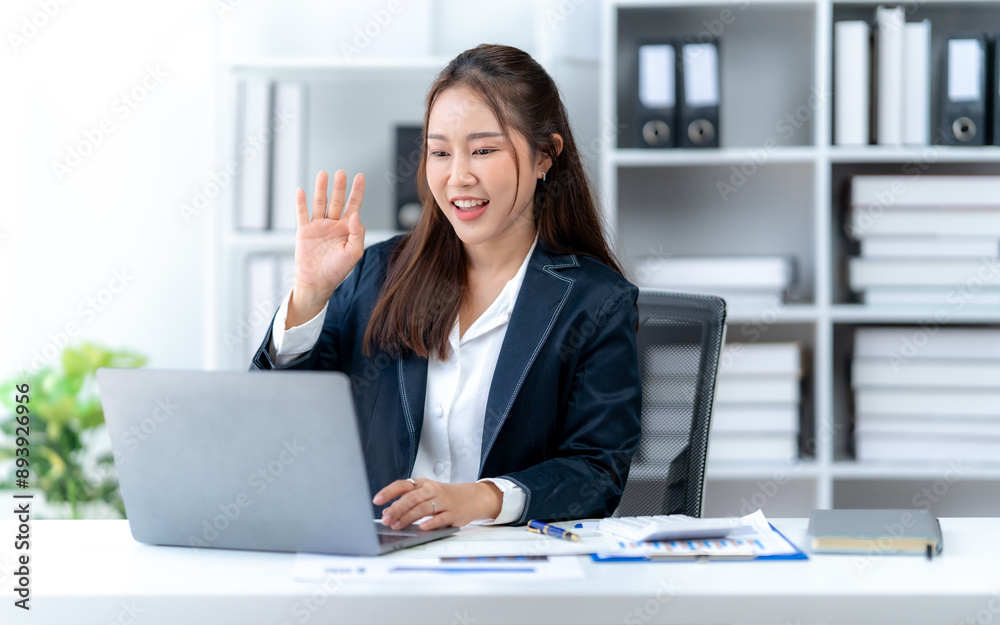 Asian business woman using computer looking at laptop and talking on video conference Asian business woman using computer looking at laptop and talking on video conference