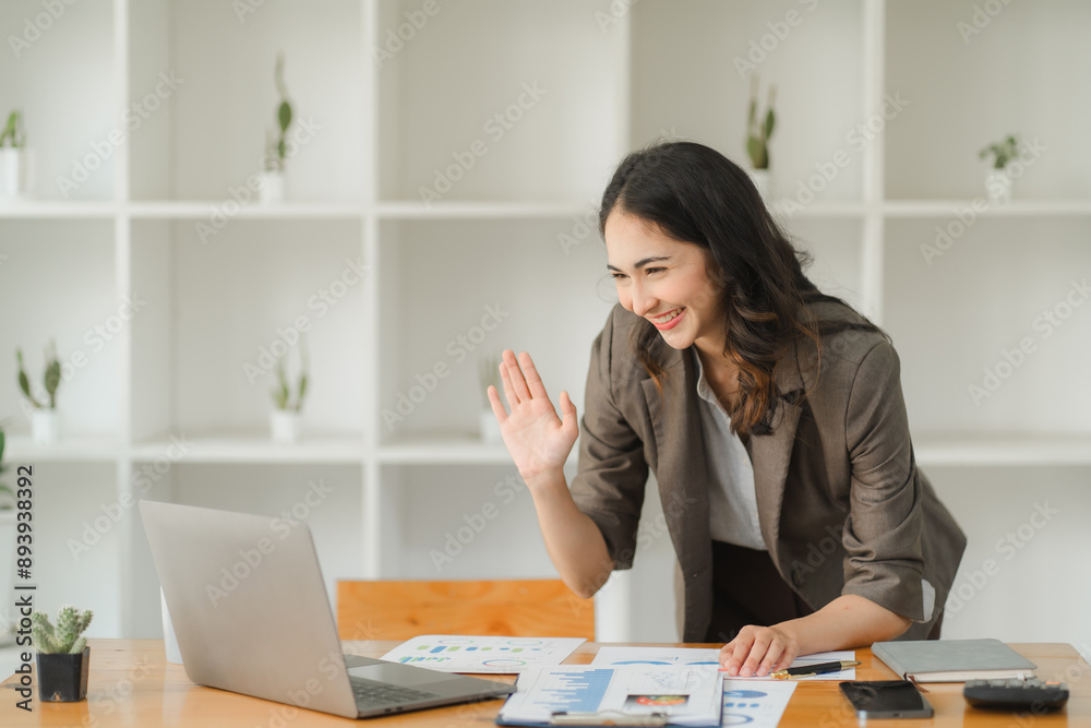 Virtual Warmth: A radiant businesswoman greets colleagues through a video call, her genuine smile reflecting the ease and connectivity of modern workspaces. Virtual Warmth: A radiant businesswoman greets colleagues through a video call, her genuine smile reflecting the ease and connectivity of modern workspaces.