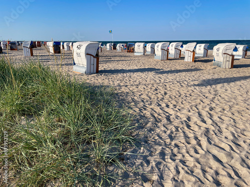 View of the sandy beach, traditional north german beach chairs strandkorb and green beach grass on Baltic sea coast