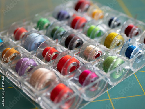 Bobbins with colored threads in the plastic box for storage. Sewing accessories concept