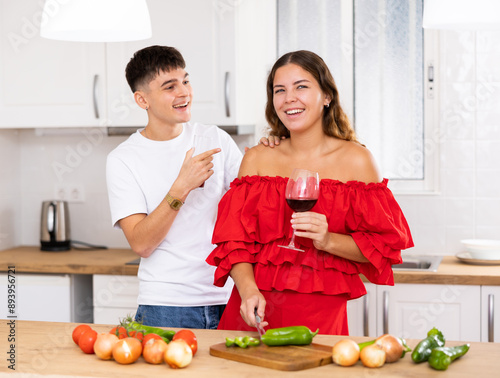 Happy family couple cooking healthy vegetable salad together in comfy home kitchen