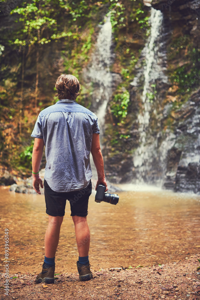 Back, hiking and photography with man at waterfall in nature for adventure, exploration or journey. Environment, jungle and travel with photographer outdoor in forest for hobby, leisure or memory Back, hiking and photography with man at waterfall in nature for adventure, exploration or journey. Environment, jungle and travel with photographer outdoor in forest for hobby, leisure or memory