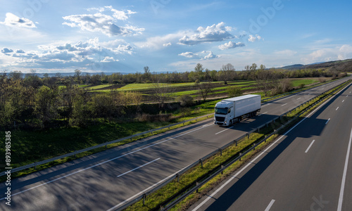White Trucks with containers on highway. Large Transportation Truck on a highway road through the countryside with blue sky and white clouds background.