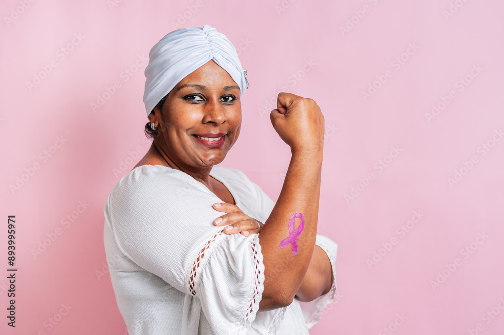 Black woman breast cancer survivor with a pink ribbon painted on her forearm with a pink background. Black woman breast cancer survivor with a pink ribbon painted on her forearm with a pink background.