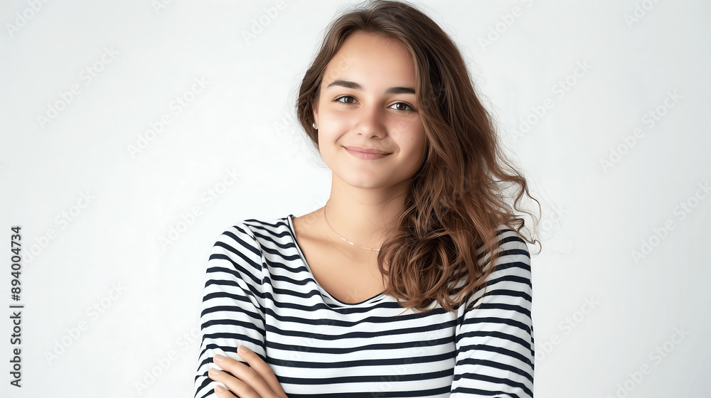 Casual portrait of a young woman with a carefree smile, wearing a striped shirt, arms crossed, and standing against a light background Casual portrait of a young woman with a carefree smile, wearing a striped shirt, arms crossed, and standing against a light background