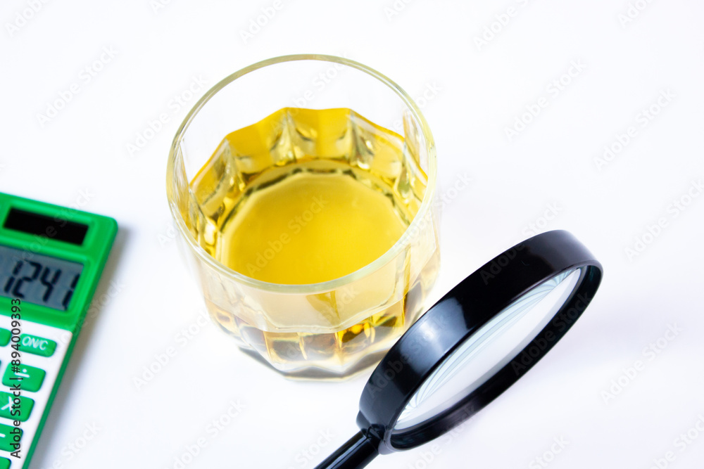 Glass of alcohol, a calculator and a magnifying glass. Cost of alcohol,research,costs,price of alcoholic beverages. Glass of alcohol, a calculator and a magnifying glass. Cost of alcohol,research,costs,price of alcoholic beverages.