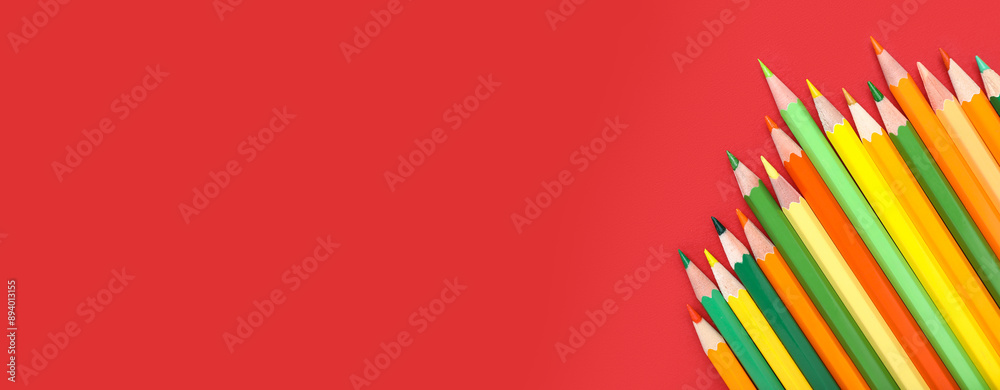 Fototapeta premium Color pencils on red background, closeup