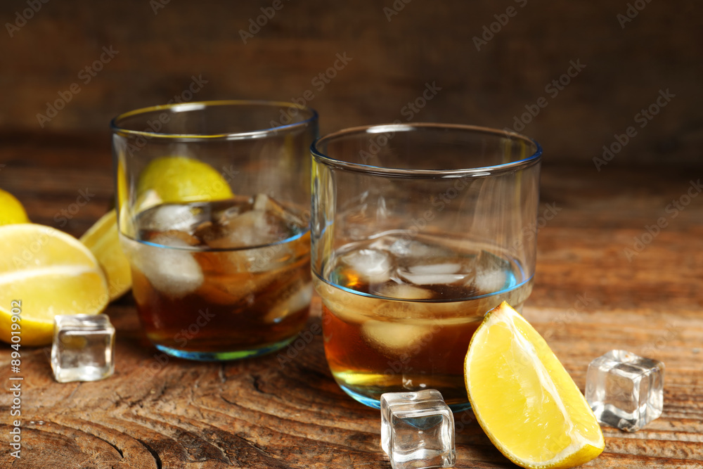 Glasses of rum with ice cubes and lime on wooden background Glasses of rum with ice cubes and lime on wooden background