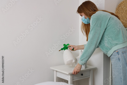 Tableau sur toile Young woman removing mold from wall over table in bedroom