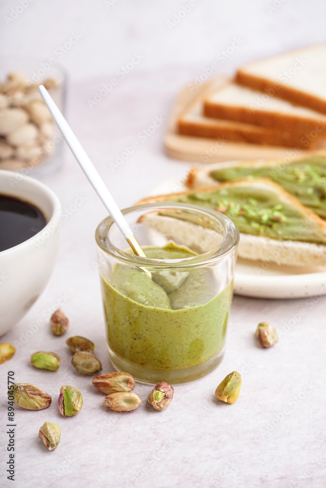Glass with tasty pistachio paste on light background Glass with tasty pistachio paste on light background