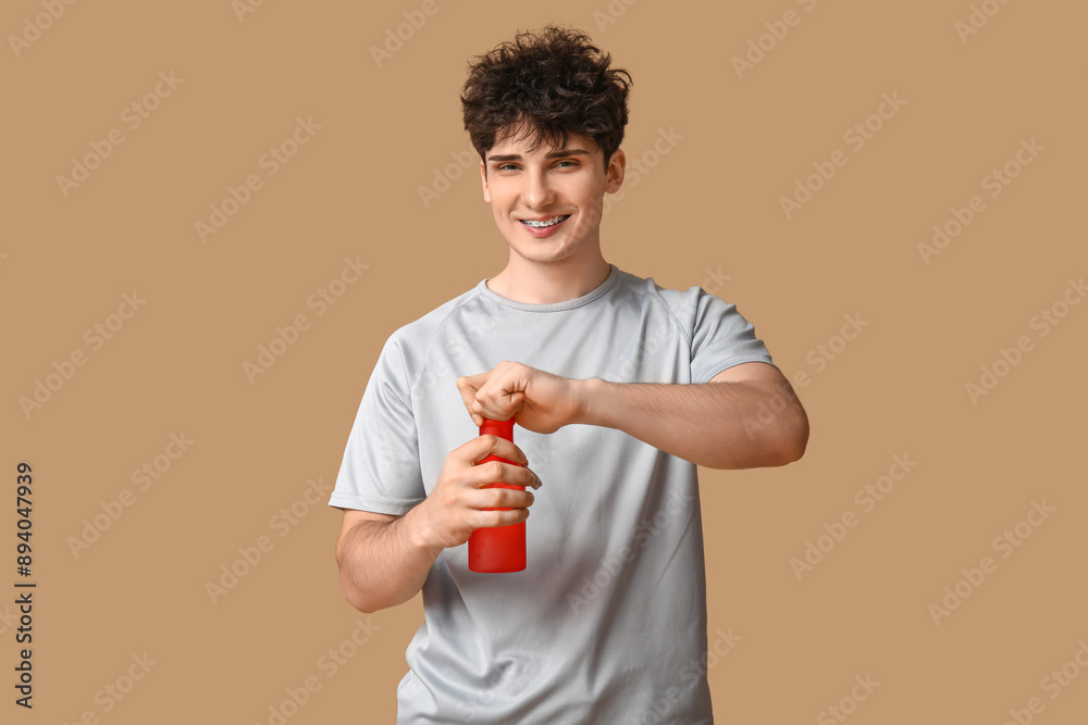 Sporty guy opening bottle of water on beige background Sporty guy opening bottle of water on beige background