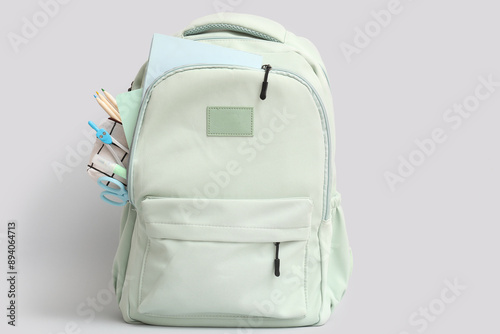 Grey school backpack with stationery and notebooks on white background