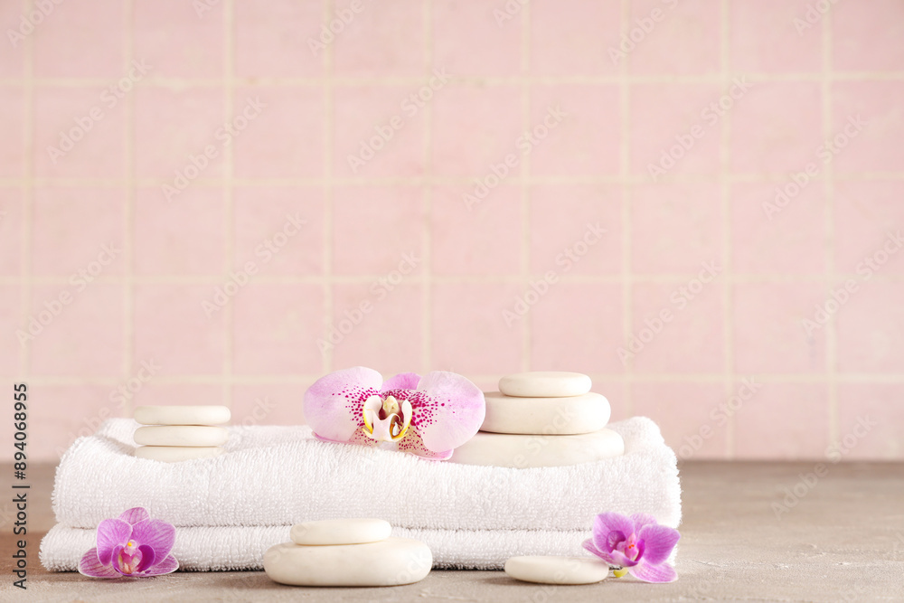 Spa stones, towel and orchid flowers on table