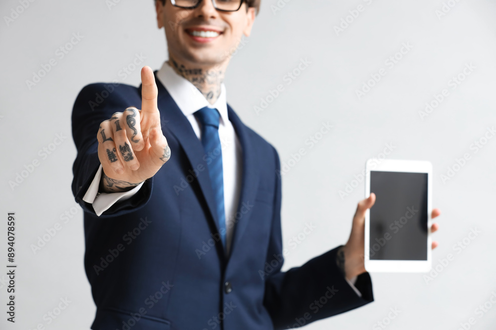 Young businessman with tablet computer using virtual screen on grey background, closeup Young businessman with tablet computer using virtual screen on grey background, closeup