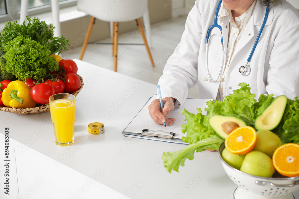 Mature female nutritionist writing on clipboard at table in office, closeup Mature female nutritionist writing on clipboard at table in office, closeup