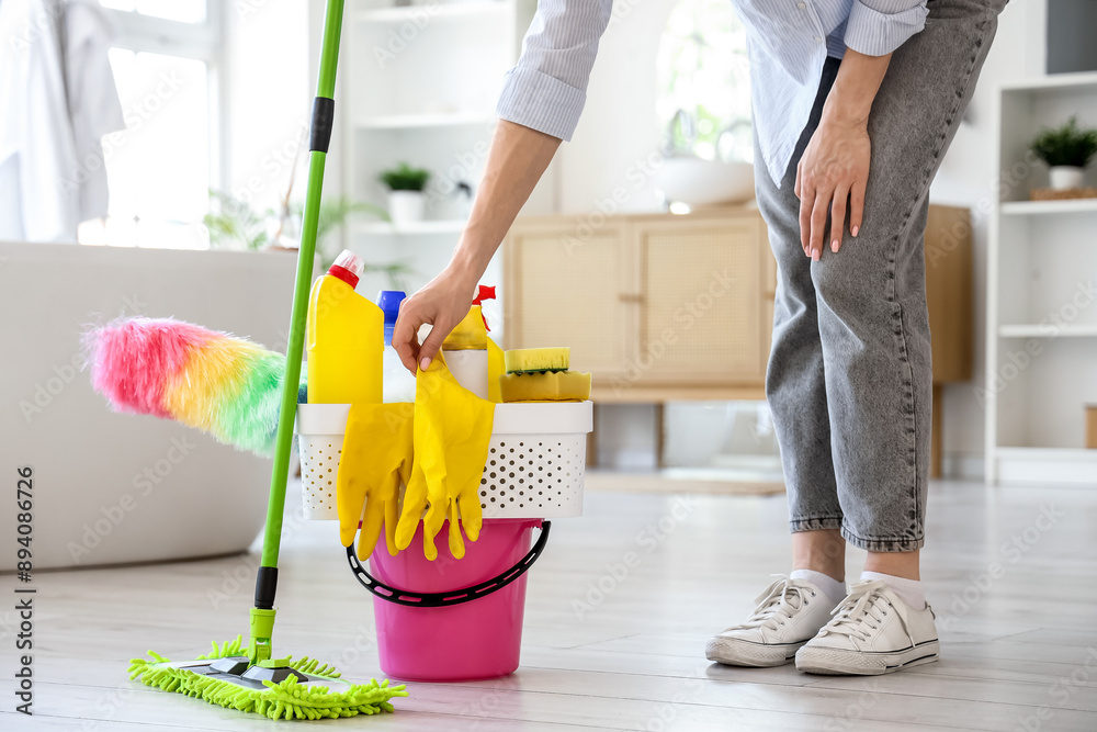 Fototapeta premium Young woman with different cleaning supplies mopping floor at home, closeup