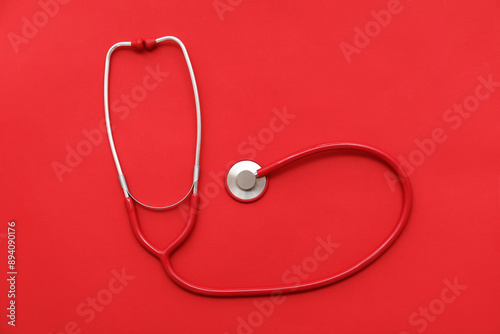 Modern stethoscope on red b...