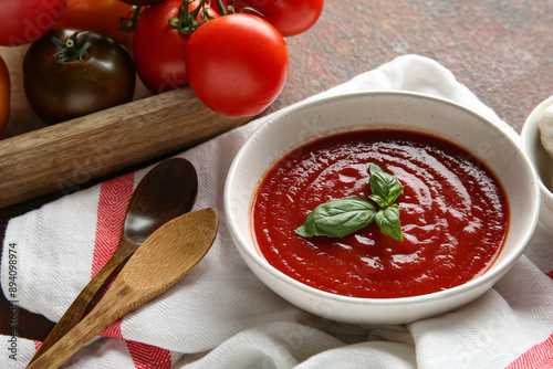Fotografie Bowl of fresh tomato soup and fresh vegetables on dark background