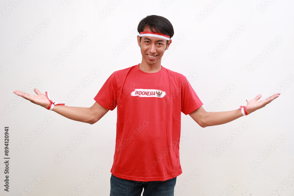 Happy asian young boy with red white ribbon celebrating Indonesia independence day while opening his palms hand