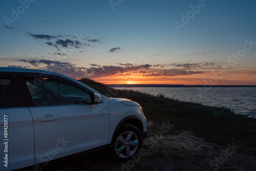 a white car at sunset by the sea