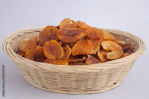 Close up of half-dried Gotgam(dried persimmon) with cross section bamboo basket and white floor, South Korea
