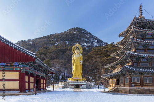 Boeun-gun, Chungcheongbuk-do, South Korea - December 26, 2022: Front view of snow covered Golden Maitreya Buddha and Palsangjeon Wooden Pagoda at Beopjusa Temple
 photo