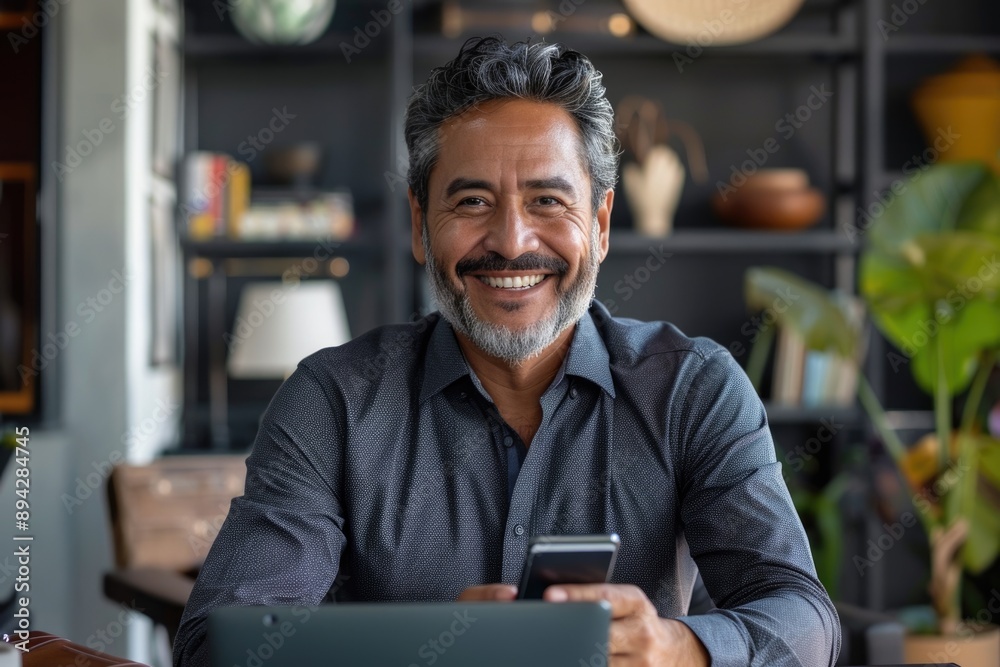 Obraz premium Middle aged Hispanic CEO working on gadgets in office.