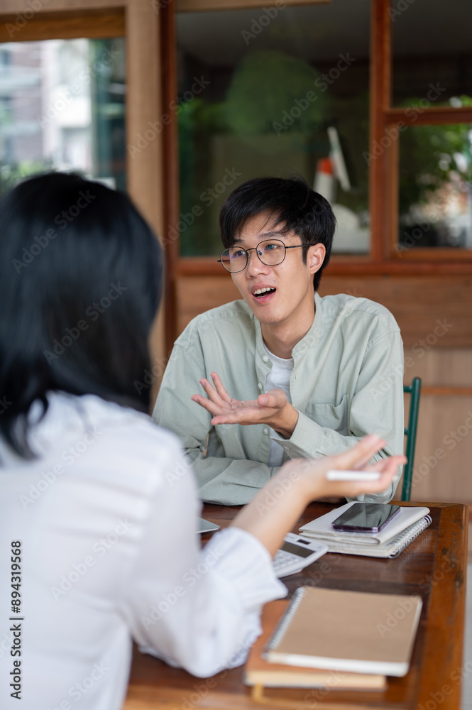 Obraz premium An Asian man is having an informal meeting with his colleague, discussing ideas for the co-project.