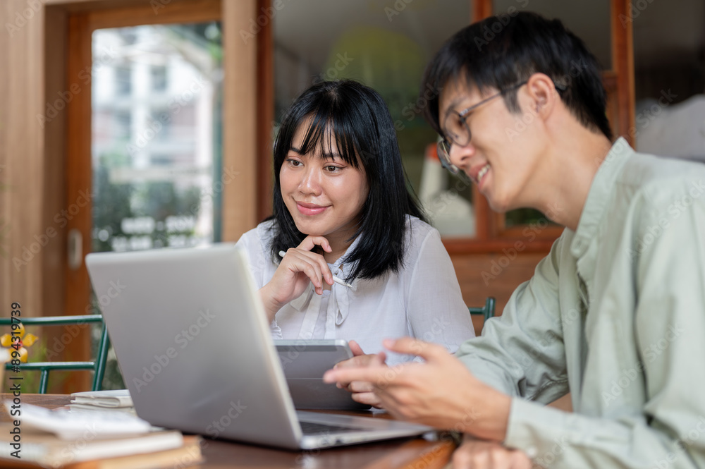 Two positive Asian male and female friends are brainstorming and discussing work at a cafe. Two positive Asian male and female friends are brainstorming and discussing work at a cafe.