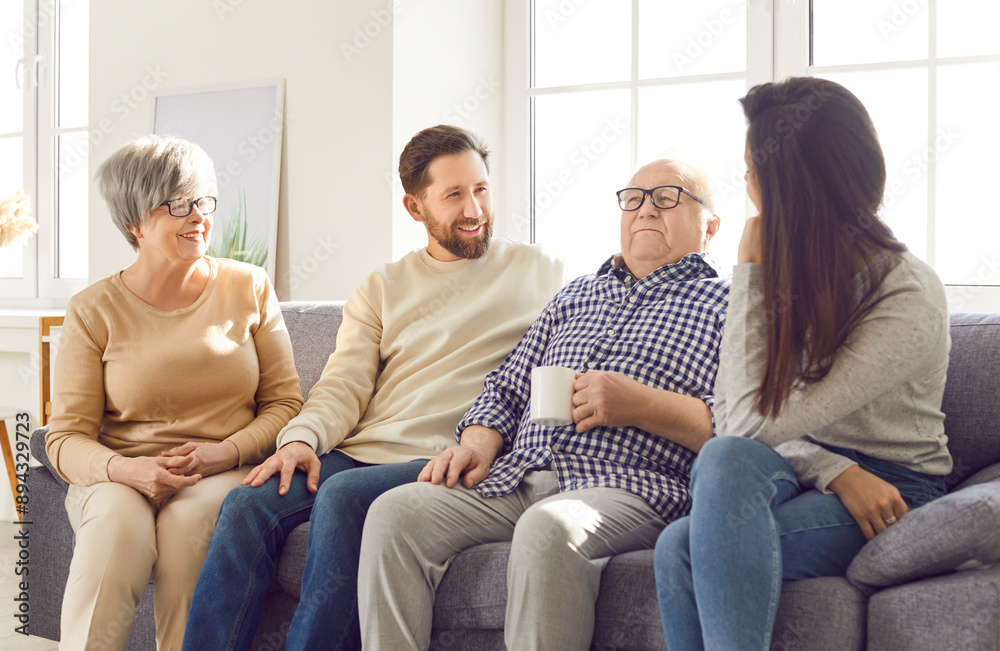 Portrait of happy joyful smiling family of senior old parents and their adult children man and woman sitting on sofa in living room at home, talking with cup of tea. Family leisure concept. Portrait of happy joyful smiling family of senior old parents and their adult children man and woman sitting on sofa in living room at home, talking with cup of tea. Family leisure concept.