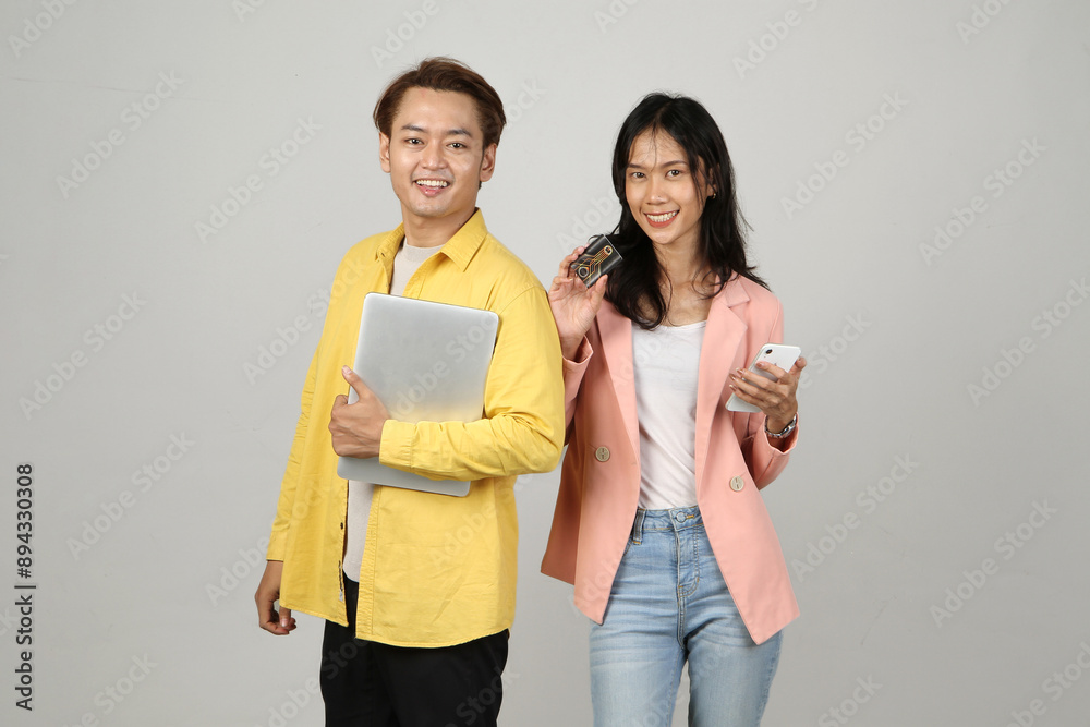 portrait of happy asian Indonesian couple holding laptop computer and phone on isolated background