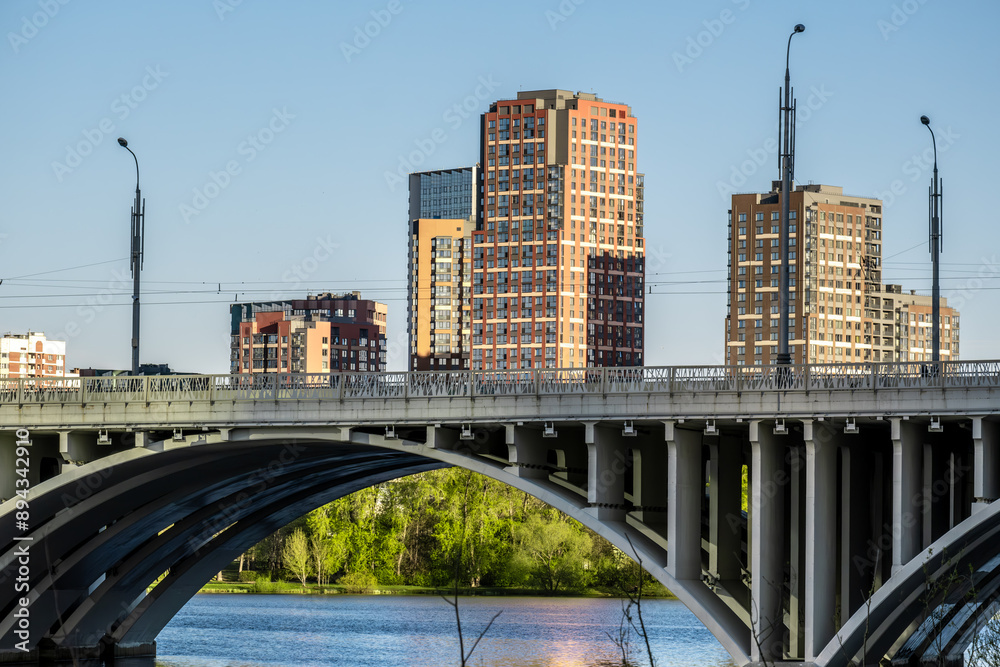 Obraz premium A concrete bridge with arches across the river in the city.