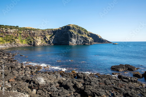 High angle view of volcanic rocks and clear sea water against Udo Lighthouse on the cliff of Tolkani Beach of Udo Island near Jeju-si, Jeju-do, South Korea
 photo