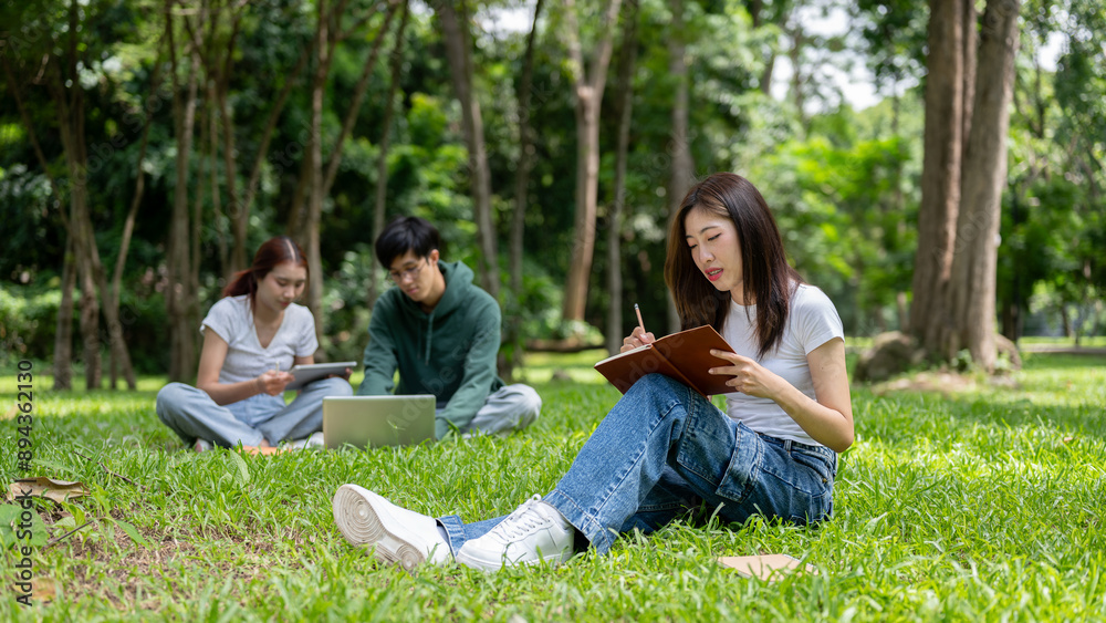 A young Asian female college student is doing homework or writing her diary in the campus park. A young Asian female college student is doing homework or writing her diary in the campus park.