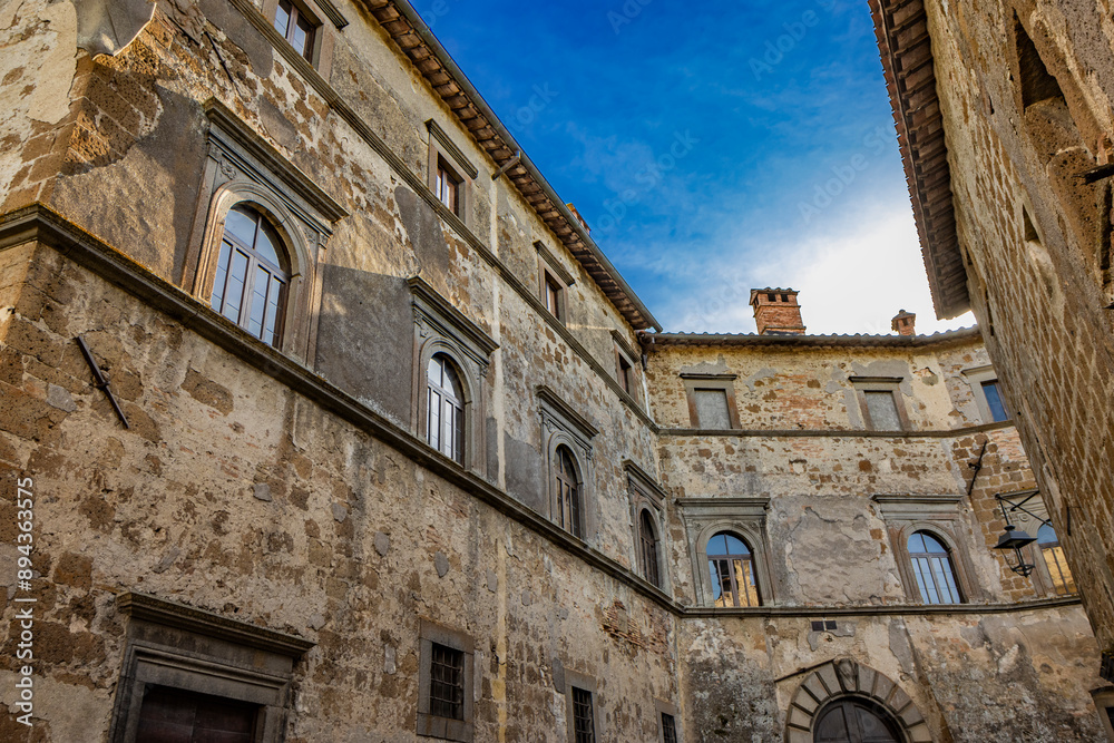 A glimpse of the ancient medieval village of Montecalvello, Viterbo, Italy. The small town dominated by the imposing castle. The inner courtyard with old stone and brick buildings. A glimpse of the ancient medieval village of Montecalvello, Viterbo, Italy. The small town dominated by the imposing castle. The inner courtyard with old stone and brick buildings.