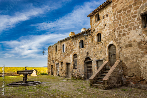 A glimpse of the ancient medieval village of Montecalvello, Viterbo, Italy. The internal courtyard of the castle with the ancient stone and brick buildings and the fountain in the center. photo