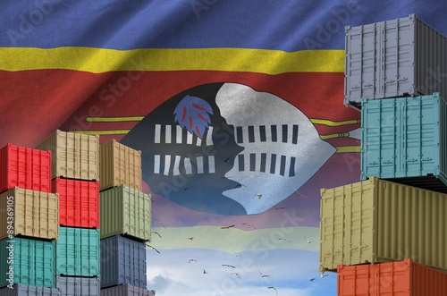 Swaziland flag and big stack of shipping cargo containers in docks with sky background close up photo