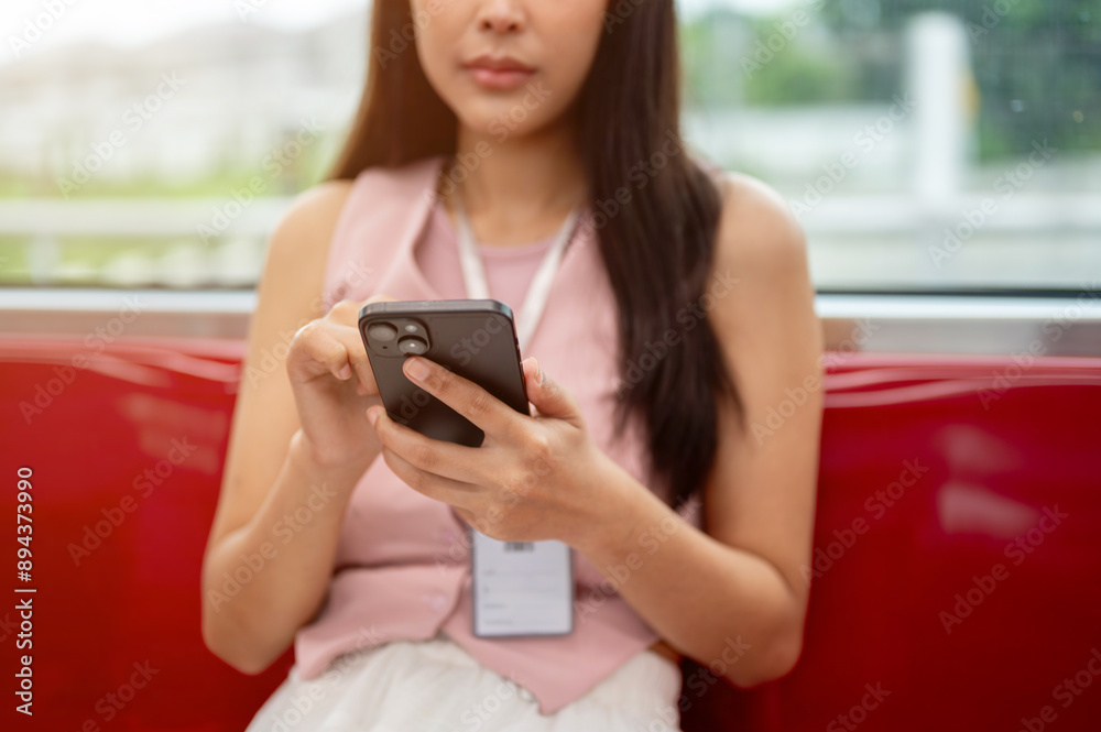 Cropped image of a thoughtful Asian female reading messages on her phone while taking the sky train. Cropped image of a thoughtful Asian female reading messages on her phone while taking the sky train.