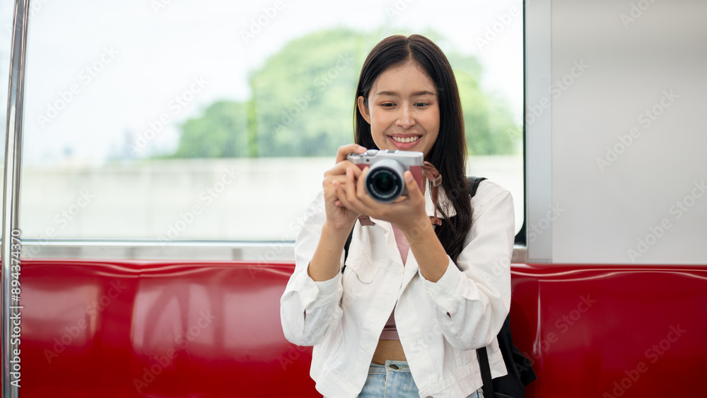 An Asian female tourist is taking pictures with her camera while commuting in a city on a sky train. An Asian female tourist is taking pictures with her camera while commuting in a city on a sky train.