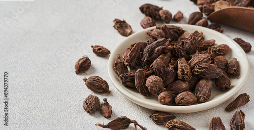 closeup pile of Amomum subulatum or black cardamom on white food background in bowl with copy space photo